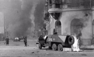 Straatgevechten in Boedapest. Op de voorgrond een kapotgeschoten Sovjet-pantserwagen.